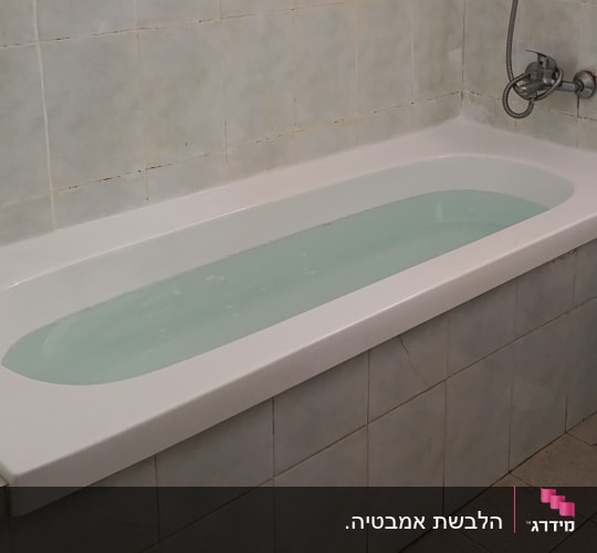 אמבטיה מלאה במים עם אריחי קרמיקה מסביב